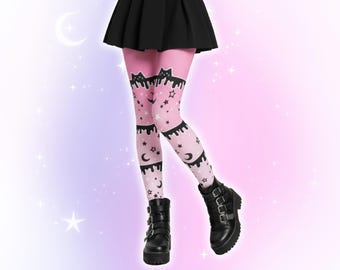 May include: Pink leggings with a pattern of black cats, stars, and crescent moons. The leggings have a black dripping design at the top and bottom. The person is wearing black platform boots with multiple buckles.