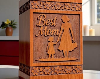 May include: A rectangular wooden box with a medium brown finish featuring a carved relief of a child holding hands with an adult. The text "Best Mom" is carved above the figures. The top and bottom borders feature a repeating floral pattern.