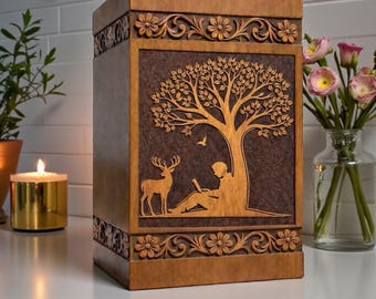 Può includere: Un'urna funeraria rettangolare in legno con un pannello centrale marrone scuro caratterizzato da un rilievo intagliato di una persona seduta sotto un albero con un cervo. I bordi superiore e inferiore presentano motivi floreali intagliati.