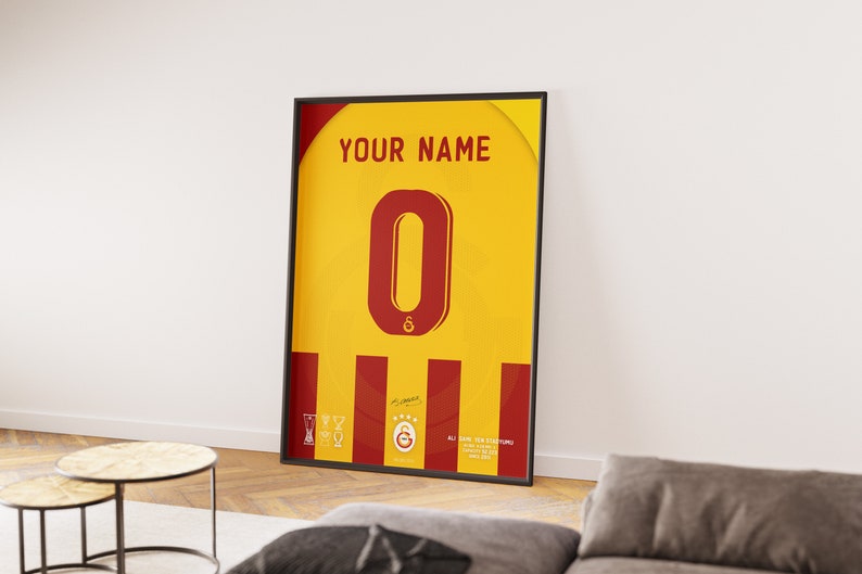 May include: A framed poster with a yellow and red design. The poster features a large red number "0" and the text "YOUR NAME". The poster also includes a red and yellow striped pattern and a small logo with a star and the letter "G".