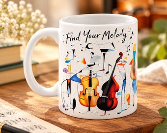 May include: A white ceramic mug featuring the text "Find Your Melody" in black script. The design includes colorful, abstract illustrations of musical instruments like a cello and double bass, along with various musical notes and shapes.