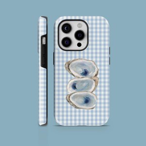 May include: A phone case featuring a blue and white gingham pattern. The case has a stack of three oyster shells with blue and white details. The side of the case is black.