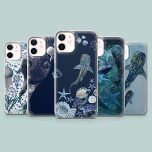 May include: A collection of five phone cases featuring marine life designs. The cases showcase illustrations of whale sharks, starfish, shells, and other sea creatures in shades of blue, white, and green. The cases are made of clear plastic.