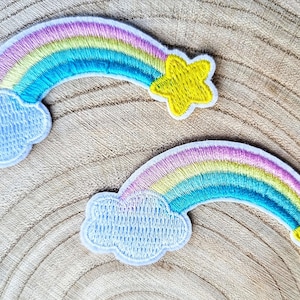 May include: Two embroidered rainbow patches with clouds and stars. The rainbows are multi-coloured with pink, yellow, green, and blue. The clouds are light blue and the stars are yellow.