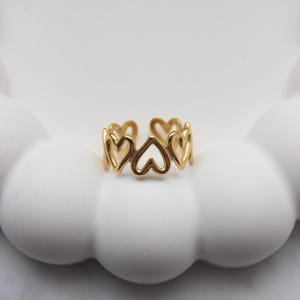 Könnte beinhalten: Goldring mit einem Design aus ineinandergreifenden Herzen.