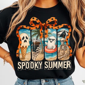 May include: Black t-shirt with a "Spooky Summer" design. The graphic features a ghost ice cream cone, a skeleton hand holding a drink, a ghost in a floatie, and a skeleton under an umbrella. The design is framed by an orange ribbon with black polka dots.