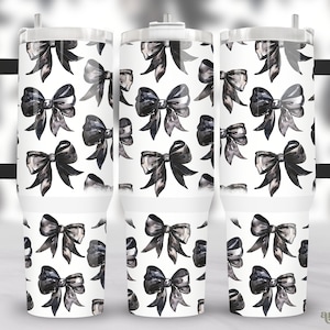 May include: Three stainless steel tumblers with a black and white watercolor bow pattern. The tumblers have a lid and a handle.