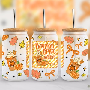 Könnte beinhalten: Drei Glasbecher mit Holzdeckeln und Metallstrohhalmen. Jeder Becher hat ein Herbst-Design mit Kürbissen, Blättern und dem Text "Pumpkin Spice Junkie". Das Design umfasst orange, gelbe und weiße Elemente.