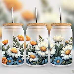 May include: Three glass tumblers with wooden lids and straws. Each tumbler features a different floral design with white daisies, yellow and orange flowers, and blue flowers on a white background.