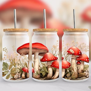 May include: Three glass tumblers with lids and straws, featuring a red and white mushroom design. The tumblers are filled with a white liquid and have a floral pattern around the mushrooms.