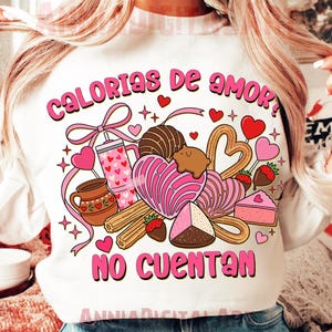 May include: White sweatshirt with a colorful graphic design featuring the text "Calorias de amor? No cuentan." The design includes hearts, sweets, and a pink bow. The sweatshirt is a crew neck style.