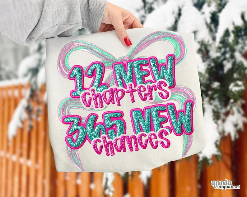 May include: A white tote bag with the text "12 NEW chapters 365 NEW chances" in teal and pink glitter lettering. The design includes teal and pink swirly ribbon accents. The bag is held by a person with red nail polish.