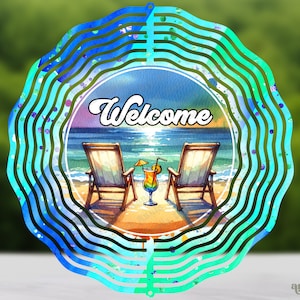 May include: A blue and green metal wind spinner with a beach scene and the word "Welcome". The scene includes two beach chairs, a sunset, and two tropical drinks.