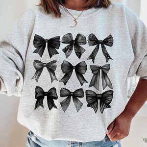 May include: A gray sweatshirt with a black and white design of nine bows. The bows are arranged in three rows of three.