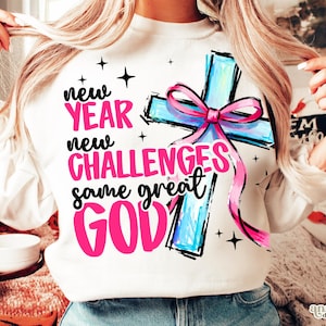 May include: White sweatshirt with a graphic design featuring a cross with a pink bow and the words "new YEAR new CHALLENGES same great GOD" in pink and black. The design includes black star accents.