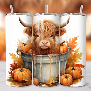 May include: A white tumbler featuring a watercolor illustration of a Highland cow in a metal bucket filled with pumpkins. The design includes autumn leaves and a straw. The tumbler is designed for cold beverages.