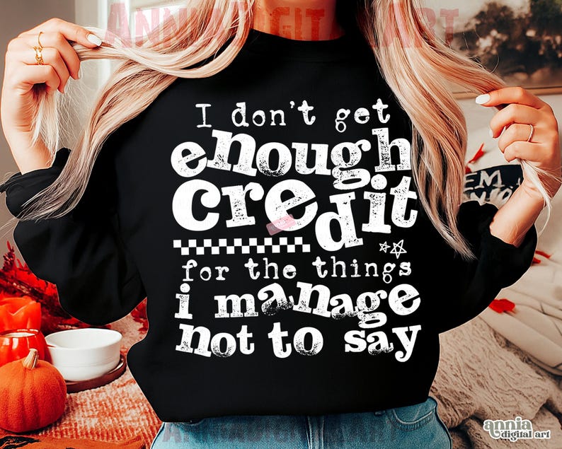 May include: Black crew neck sweatshirt with the text "I don't get enough credit for the things I manage not to say" in white. The sweatshirt has a checkered pattern and star graphic.