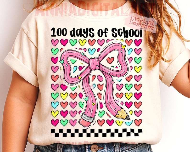 May include: Cream-colored t-shirt with the text "100 days of School." The shirt features a pink pencil shaped like a bow, surrounded by colorful hearts. A black and white checkered pattern is at the bottom.
