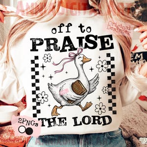 Può includere: Felpa bianca con la scritta "off to PRAISE THE LORD" e un'oca dei cartoni animati che tiene in mano una Bibbia. L'oca ha un fiocco rosa ed è circondata da fiori e stelle. Il disegno è incorniciato da un motivo a scacchi in bianco e nero.