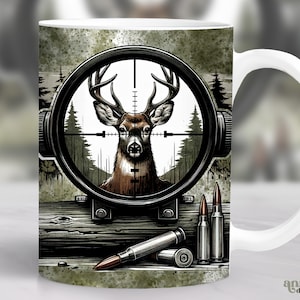 May include: White ceramic coffee mug featuring a graphic of a deer in a rifle scope with bullets on a wooden surface. The background is a green and brown camouflage pattern.
