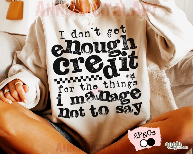 May include: Cream-colored sweatshirt with the text "I don't get enough credit for the things I manage not to say" in black. The design includes a star and a checkered pattern. The sweatshirt is a casual style.