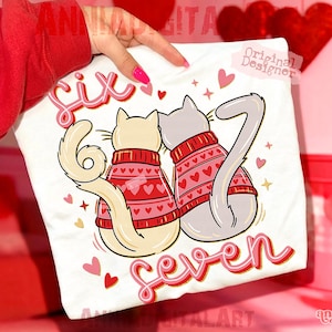 May include: White t-shirt with a design of two cats in red heart-patterned sweaters. The words "Six" and "Seven" are written in red script. Pink hearts and stars surround the cats.