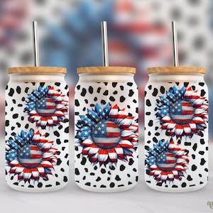Puede incluir: Tres vasos blancos con un estampado de dálmata en blanco y negro y un diseño de girasol rojo, blanco y azul. Cada vaso tiene una tapa de madera y una pajita de acero inoxidable.