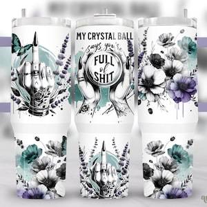 May include: A white stainless steel tumbler with a black and white floral design and a middle finger with a ring on it. The tumbler has a purple lid and handle. The text on the tumbler reads "My Crystal Ball Says You're Full of Shit".