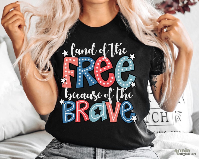 以下が含まれることがあります： 白い星が散りばめられた、赤、白、青の文字で「land of the free because of the brave」と書かれた黒いTシャツ。