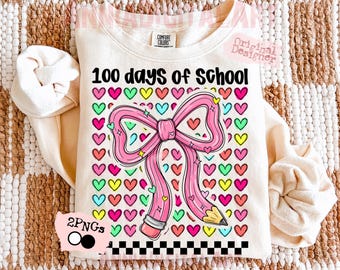May include: Cream-colored sweatshirt with the text "100 days of school" and a pink pencil-shaped bow. The bow is surrounded by colorful hearts. A black and white checkered pattern is at the bottom of the design.