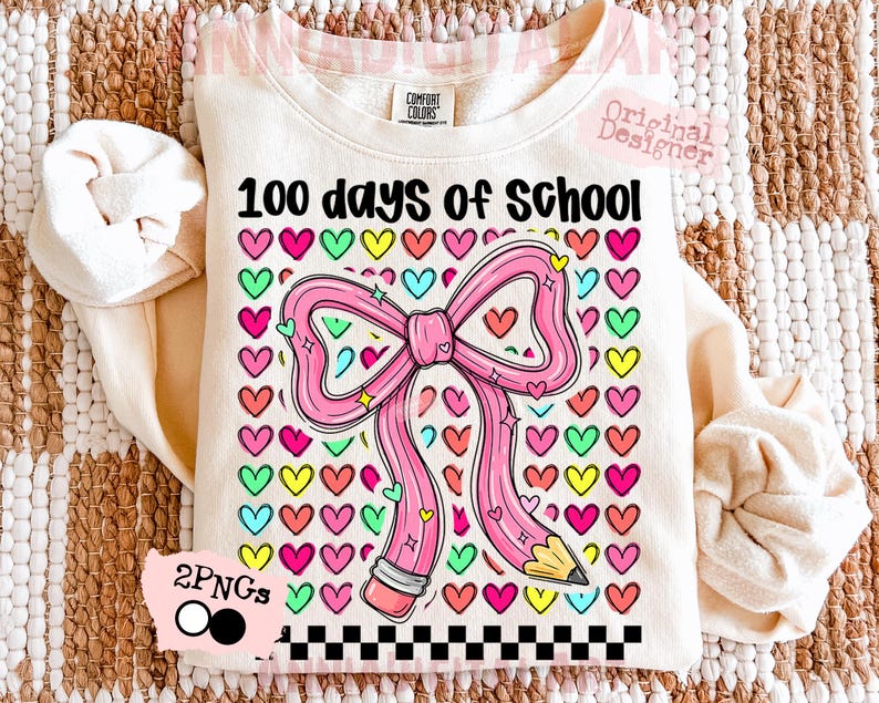 May include: Cream-colored sweatshirt with the text "100 days of school" and a pink pencil-shaped bow. The bow is surrounded by colorful hearts. A black and white checkered pattern is at the bottom of the design.