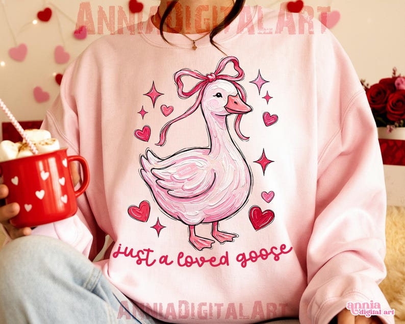 Pu&ograve; includere: Felpa rosa chiaro con un'illustrazione di un'oca rosa, un fiocco, cuori e stelle. La scritta "just a loved goose" &egrave; in rosa. Il design ha un tema romantico, adatto per San Valentino o come regalo.