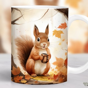 May include: White ceramic mug featuring a brown squirrel holding a brown mug. The squirrel is surrounded by autumn leaves in shades of orange, yellow, and red. The mug has a white handle.