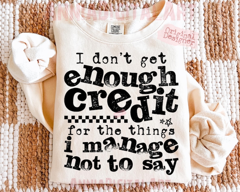 May include: Cream-colored sweatshirt with the text "I don't get enough credit for the things I manage not to say" in black. The sweatshirt has a crew neck and long sleeves. The text is in a bold, playful font.