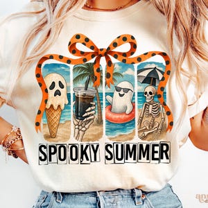May include: Cream-colored t-shirt with a "Spooky Summer" graphic. The design features a ghost ice cream cone, a skeleton holding a drink, a ghost in a floatie, and a skeleton under an umbrella. An orange bow with black polka dots tops the design.