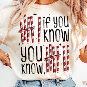 May include: Cream-colored sweatshirt with the text "If you know, you know" in black, accompanied by red and white candy cane graphics. The design includes small black star accents.