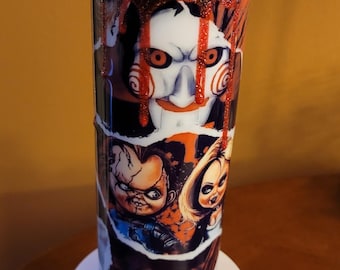 May include: A tall, cylindrical tumbler featuring a horror movie theme. The design includes images of characters from the Saw and Chucky franchises, with a red and black color scheme. The lid is topped with a small figurine and decorative ice-like elements.