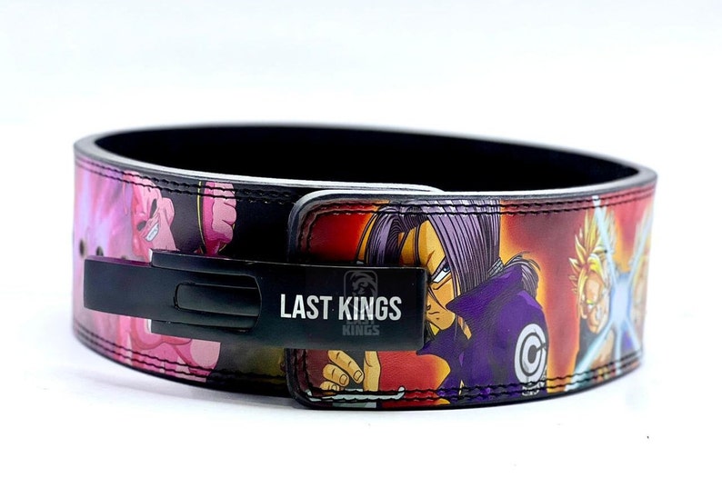 Puede incluir: Un cintur&oacute;n de levantamiento de pesas negro con un estampado de anime colorido que presenta personajes de Dragon Ball Z. El cintur&oacute;n tiene una hebilla de metal negro con las palabras "Last Kings" impresas en &eacute;l.