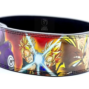 Puede incluir: Un cintur&oacute;n de levantamiento de pesas de cuero negro con un estampado colorido de personajes de anime de Dragon Ball Z. El cintur&oacute;n tiene el texto "Last Kings" en blanco.