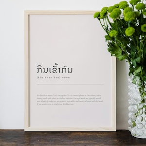 Könnte beinhalten: Ein gerahmter Druck mit weißem Hintergrund und schwarzem Text. Der Text ist in Lao und Englisch. Der Lao-Text lautet "ກິນເຂົ້າກັນ" und der englische Text lautet "kin khao kan", was "Lasst uns zusammen essen" bedeutet.