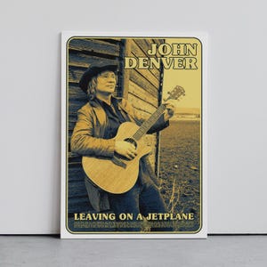 Puede incluir: Un póster enmarcado con John Denver tocando la guitarra. El póster tiene una estética vintage con el texto "JOHN DENVER" en la parte superior y "LEAVING ON A JETPLANE" en la parte inferior. La imagen está sobre un fondo neutro.