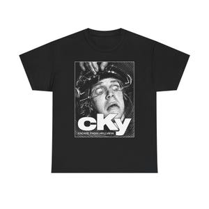 May include: Black t-shirt featuring a black and white graphic of a person with wide eyes and a headpiece. The graphic includes the word "cKy" and the text "ESCAPE FROM HELLVIEW".