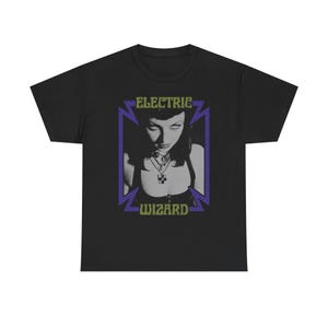 May include: Black t-shirt featuring a graphic of a woman with dark hair and a necklace, framed by a purple and green design. The text "ELECTRIC WIZARD" is displayed above and below the image.