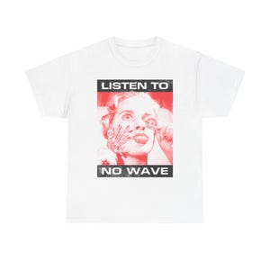 May include: White t-shirt featuring a red and black graphic. The graphic includes the text "LISTEN TO" above a distressed image of a woman's face, and "NO WAVE" below. The design has a vintage, grunge aesthetic.