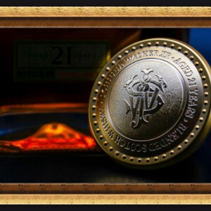 May include: A gold-colored round metal bottle stopper with the words "Johnnie Walker Aged 21 Years" and "Scotch Whisky" engraved on it.