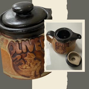 May include: A brown ceramic jar with a lid, featuring a dark brown rim and a relief design of a person cooking with the text OLIVERS embossed on the front. The jar has a textured tan body and a matching dark brown lid with a central knob handle.