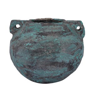 Op de afbeelding: Een ronde, getextureerde, turquoise en grijze keramische pot met twee kleine handvatten, elk met een gat. De pot heeft een brede opening en een ruwe, verouderde uitstraling, wat suggereert dat het een antiek of vintage stuk is.