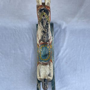 以下が含まれることがあります： 手描きの木製ロッキングホース。 白いボディに赤、黄、青のアクセント。 緑色のベースに取り付けられた、クラシックなおもちゃです。
