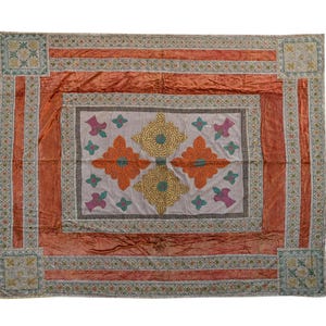 May include: A rectangular textile with a central design and border. The centre features a light grey background with orange, yellow, and purple floral patterns. The border is a rust colour with a decorative pattern. The corners have square designs.