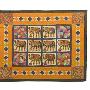 May include: A colorful, square textile featuring a repeating pattern of embroidered elephants in a grid. The quilt has a yellow border with diamond and square accents, and decorative corner designs. The elephants are brown with colorful details.